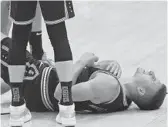  ?? JOHN BAZEMORE/AP ?? Hawks guard Bogdan Bogdanovic lies on the court after a knee injury during the first half of Game 6 against the 76ers on Friday in Atlanta.