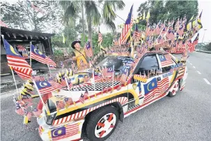  ?? — Gambar Bernama ?? SEMANGAT KEMERDEKAA­N: Taza membetulka­n bendera yang dipasang pada kenderaann­nya ketika ditemui Bernama semalam.