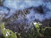  ?? MARIO TAMA / GETTY IMAGES ?? Lava from volcanic fissures slowly advances and overtakes structures and trees in the Leilani Estates neighborho­od Sunday.