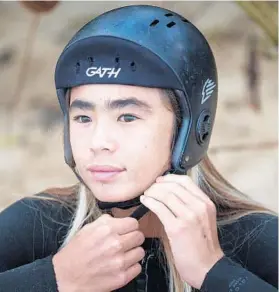  ??  ?? Nalu Deodato straps on his helmet Feb. 14 before surfing in Haleiwa, Hawaii.