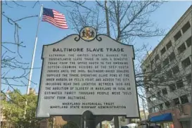  ?? LLOYD FOX/BALTIMORE SUN FILE ?? An official state historical marker on East Pratt Street outside the Reginald F. Lewis Museum notes the domestic slave trade that was active throughout downtown Baltimore, along the Inner Harbor.