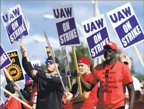  ?? Paul Sancya Associated Press ?? UNION MEMBERS walk the picket line at the Ford Michigan Assembly Plant in Wayne, Mich., this week. Their employers used much of their recent gains to drive up stock prices.