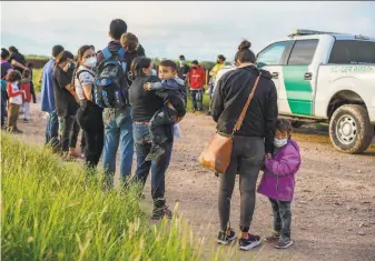  ?? Paul Ratje / AFP via Getty Images ?? Migrant families are processed by U.S. Border Patrol agents after crossing the border Thursday in Penitas, Texas. Immigratio­n advocates welcomed President Biden’s new policy.