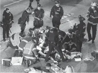  ?? JAMES ANDERSON VIA AP ?? Emergency workers tend to an injured person on the ground after a driver sped through a protest-related closure on Interstate 5 in Seattle early Saturday. The driver was arrested.