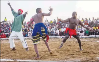  ??  ?? The referee, left, awards a point to the dambe boxer in blue during a Nigeria Traditiona­l Boxing League match March 18 in Nasarawa State, Nigeria.