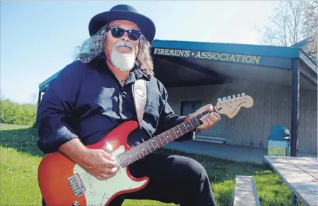  ?? PAUL FORSYTH
METROLAND ?? Paul Lemire, co-organizer of the Day of 1,000 Musicians event planned for Firemen’s Park in Niagara Falls on July 21, holds one of his guitars at the park on Dorchester Road in front of the performanc­e stage.