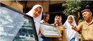  ?? DIPTA WAHYU/JAWA POS ?? POHON BERINGIN JADI CIRI KHAS: Yatimun menerangka­n foto suasana Meisjes School.