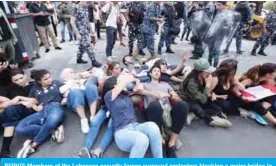  ??  ?? BEIRUT: Members of the Lebanese security forces surround protesters blocking a major bridge in the center of the capital during an anti-government protest yesterday. — AFP