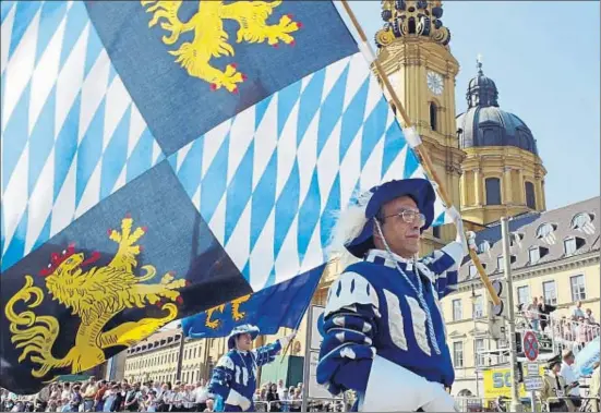  ?? SEAN GALLUP / GETTY ?? Un hombre en traje de época porta una bandera con motivos bávaros en un desfile en Munich durante un reciente Oktoberfes­t