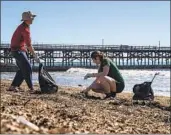  ?? Gina Ferazzi Los Angeles Times ?? VOLUNTEERS pick up trash that washed ashore in Seal Beach following several recent storms.