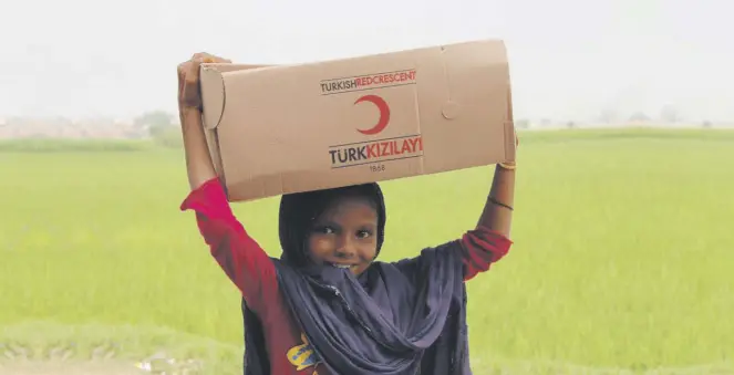  ??  ?? A girl carries on her head an aid package which the Turkish Red Crescent distribute­d on Eid al-Adha in northweste­rn Pakistan, Aug. 23, 2018.