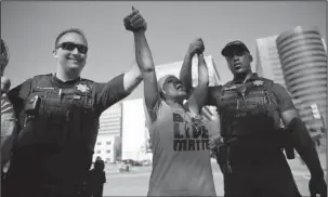  ?? The Associated Press ?? HOLDING HANDS: Angie Pitts, of Tulsa, holds hands with Tulsa Police officers while protesting the death of Terence Crutcher, who was shot by police, in front of the Tulsa Country Courthouse on Thursday in Tulsa, Okla.