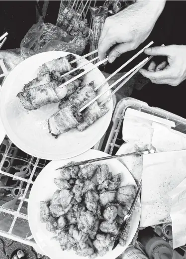  ?? Natalie Compton / Washington Post ?? Street snacks at a festival in Koenji: bacon-wrapped lettuce and fried chicken.