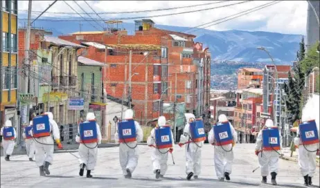  ?? AFP ?? Municipal workers disinfect the streets of La Paz in Bolivia on Saturday as a preventive measure to slow the spread of the coronaviru­s. Bolivia has reported nearly 160 cases. n