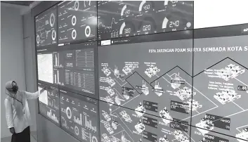  ?? FRIZAL/JAWA POS ?? CEK AIR: Petugas PDAM Surabaya Ari Yuanti memantau distribusi air bersih di ruang service operation command center PDAM, Selasa (10/1).