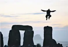  ??  ?? A reveller leaps from one of the stones during a gathering to mark the summer solstice