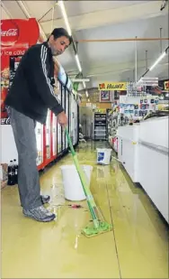  ??  ?? Water woes: Titahi Bay Four Square owner Ketan Kansera was left mopping up an inch of water after his shop flooded last Monday night.