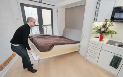  ?? GLENN BAGLO/ PNG FILES ?? Tenant Andrew Haas opens his bed at his 291- square- foot apartment in the Burns Block building on Hastings Street.