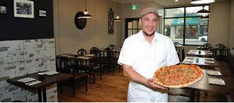  ??  ?? Owner Frank Donato holds a freshly baked pizza pie inside the new restaurant, an attractive blend of modern Euro and urban industrial design in the heart of South Walkervill­e.