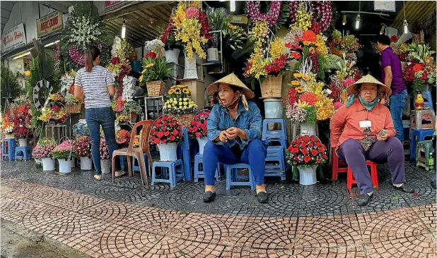  ?? Photos: ROSS GIBLIN/FAIRFAX NZ ?? Flower sellers outside the Ben Thanh Market, a feast for shoppers, amateur photograph­ers, and those with a strong constituti­on.