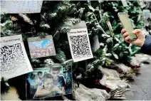  ?? ?? A person uses a phone in front of QR codes for donations to help Palestinia­ns displayed on Christmas trees in Moscow on December 29. (AFP)