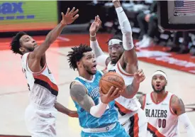  ?? STEVE DYKES/AP ?? Hornets forward Miles Bridges, center, drives to the basket on Trail Blazers forward Derrick Jones Jr., left, and forward Robert Covington, right, during the first half on Monday.