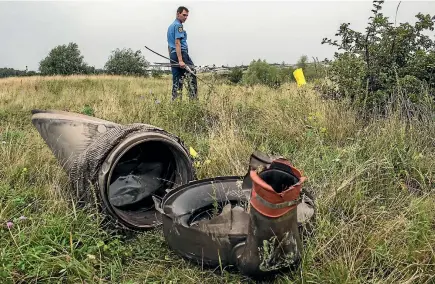  ?? GETTY IMAGES ?? A Ukrainian police officer searches for human remains after Air Malaysia flight MH17 travelling from Amsterdam to Kuala Lumpur crashed on the Ukraine/russia border.