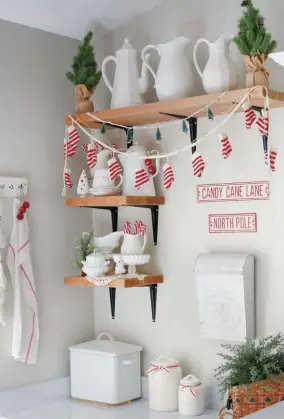  ??  ?? |TOP LEFT| CANDY CANE KITCHEN. A cozy desk nook in the kitchen became a creative corner for Christmas cheer once Desirée added some shelves. “It was an empty wall when we moved in, so I put in open shelves I made myself to display and change out seasonal décor,” she says. Keeping it simple with red-and-white décor, miniature trees and Christmas-inspired signs, Desirée designated this space for classic Christmas colors. |TOP RIGHT| ALL BOTTLED UP. A vintage secretary desk in the master bedroom houses Desirée’s collection of glass bottles and jars. “I added the thrifted flower wallpaper to give the piece some soft color,” she says. Miniature bottlebrus­h trees are scattered among the collection to hint at the holiday.