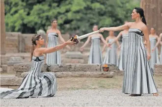  ?? | EPA-EFE / GEORGE VITSARAS ?? OLYMPIC RITUAL
GREEK actress Mary Mina, right, playing the role of High Priestess, lights a pot with the torch of the Olympic Flame during the Olympic Flame lighting ceremony for the Paris 2024 Summer Olympic Games, in front of the Hera Temple at the Ancient Olympia site in southern Greece. The Olympic Games will be held in Paris from July 26 to August 11.