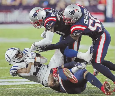  ?? STAFF PHOTO BY MATT STONE ?? CORNERING A RUNAWAY COLT: Indianapol­is running back Nyheim Hines (left) gets taken down by a host of Patriots defenders, including Jason McCourty (top) and Nicholas Grigsby (50), in Thursday night’s Patriots victory over the Colts at Gillette Stadium in Foxboro.