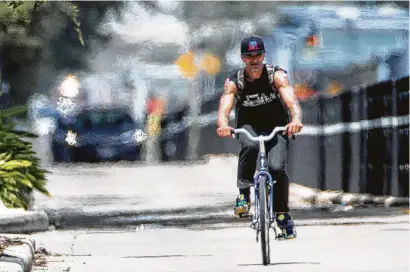  ?? Jon Shapley / Staff photograph­er ?? A man rides a bike down Main Street in downtown Houston. The area was under a heat advisory, and the National Weather Service said the heat index could reach 110 degrees.