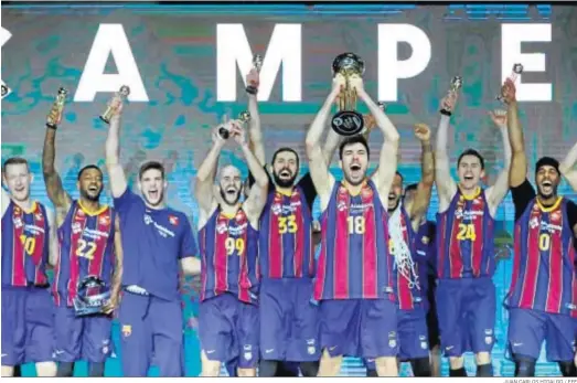  ?? JUAN CARLOS HIDALGO / EFE ?? Pierre Oriola alza el trofeo de campeón de la Copa del Rey en la habitual cancha del Real Madrid con todo el Barcelona festejando detrás.