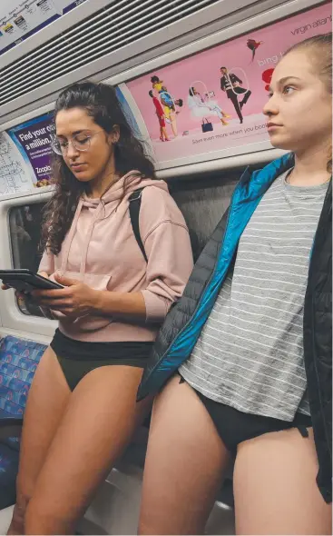 ?? Picture: AFP ?? BARE MINIMUM: Passengers read while riding a Jubilee Line train as they take part in the annual 'No Trousers On The Tube Day' on the London Undergroun­d.
