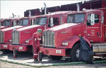  ?? PHOTO: BLOOMBERG ?? A Halliburto­n worker makes notes while standing next to trucks at an Anadarko Petroleum Corporatio­n. The company’s merger with Baker Hughes may enable it to slash as much as $2bn of costs.