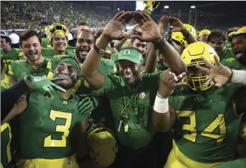  ?? AP PHOTO/CHRIS PIETSCH ?? In this Sept. 2 file photo, Oregon coach Willie Taggart (center), throws the “O” to fans as he celebrates with his team after a 77-21 victory over Southern Utah in an NCAA college football game in Eugene, Ore. The Oregon Ducks have caught on to new...