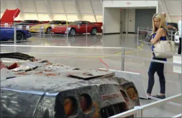  ?? PHOTOS BY THE ASSOCIATED PRESS ?? In this Wednesday photo, Stacy Jorgensen of Los Angeles examines a display of the cars that were swallowed by the sinkhole at the National Corvette Museum in Bowling Green, Ky. The car-swallowing hole has been fixed but not forgotten at the museum....