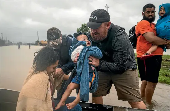  ?? PHOTO: WASHINGTON POST ?? Glenda Montelonge­o, Richard Martinez and his two sons are helped out of a boat after being rescued in Houston yesterday. Nearly 35,000 people are in the city’s emergency shelters.