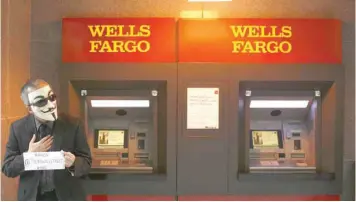  ?? — Reuters ?? A man wearing a mask stands near an ATM machine during a protest outside Wells Fargo bank in New York.