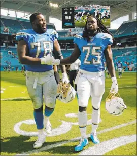  ?? Michael Reaves Getty Images ?? MELVIN GORDON, right, walks off the field in Miami with Trent Scott after the Chargers’ victory over the Dolphins on Sunday. Gordon didn’t play.