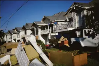  ?? Rebecca Blackwell / Associated Press ?? Snowbird Bob Fennessey of Montreal, Canada, clears out storm-damaged items from his condo, as ruined furniture and a car from his neighbors’ vacation home sits on the lawn, after storm surge filled the first story of their houses during the passage of Hurricane Ian, near San Carlos Boulevard in Fort Myers Beach, Fla., on Sunday.