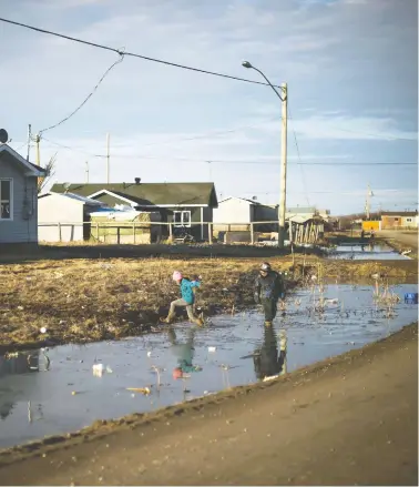  ?? THE CANADIAN PRESS/FILES ?? Indigenous children play in water-filled ditches in Attawapisk­at, Ont. Ottawa is grappling with how best to compensate Indigenous children who were unnecessar­ily removed from their families and communitie­s.