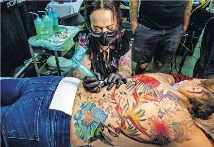  ??  ?? Tattoo artist Renee Little works on a client's back piece tattoo during the Oklahoma City Tattoo Arts Convention on Friday at the Cox Convention Center. [CHRIS LANDSBERGE­R PHOTOS/ THE OKLAHOMAN]