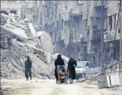  ??  ?? Civilians walk along a destroyed street in the former rebel-held town of Harasta in Eastern Ghouta in 2018.
AFP