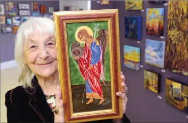  ?? GARY NYLANDER/The Daily Courier ?? Eveline Wallace holds her painting Archangel Michael, painted with egg tempera and a bit of vodka, at the Lake Country Art Gallery. Wallace’s painting and hundreds of others are part of the eighth annual Under 100 Exhibition, with most of the artwork...