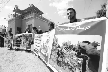  ??  ?? People hold banners showing victims of Saudi-led air strikes during a demonstrat­ion outside the United Nations offices in Sanaa, Yemen. — Reuters photo