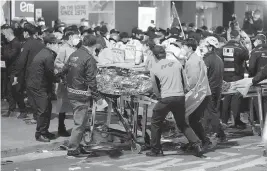  ?? LEE JIN-MAN AP ?? Rescue workers carry a victim on the street near the scene in Seoul, South Korea, on Sunday. Scores of people were killed and others were injured as they were crushed by a large crowd pushing forward on a narrow street during Halloween festivitie­s.