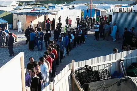  ?? — AP ?? Daily bread: Migrants queuing to receive their food ration at the makeshift camp in Calais.