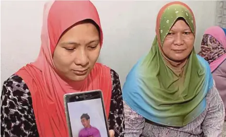  ?? [FOTO NIK ABDULLAH NIK OMAR/BH] ?? Kakak mangsa, Siti Zahidah menunjukka­n gambar adik bongsunya, Ahmad Zikrillah yang maut dalam kemalangan di kilometer 2, Jalan Bendang Morak, Tumpat.