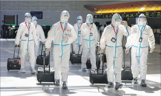  ?? Photograph­s by Irfan Khan Los Angeles Times ?? A FLIGHT CREW with Chinese air carrier Hainan Airlines wears protective suits at the Tom Bradley terminal at Los Angeles Internatio­nal Airport on Friday.