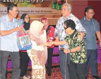  ??  ?? Awang Tengah assists a recipient of Gawai Dayak aid who is being greeted by Fatimah.